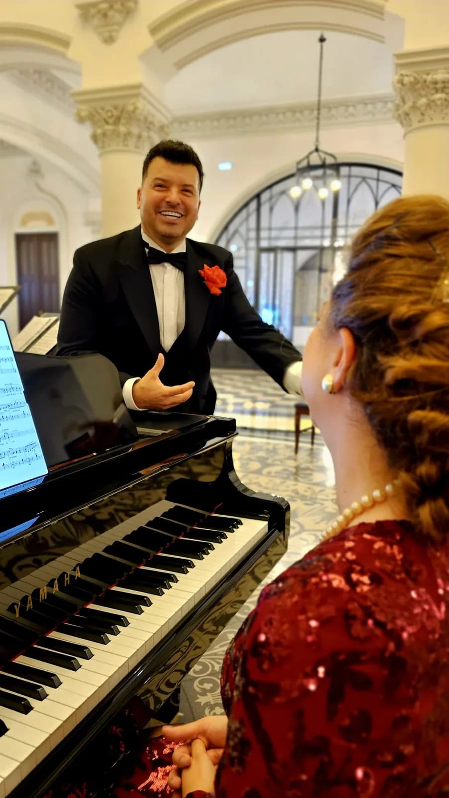 Gabriel Bîrjovanu în frac, la pian, alături de pianistă, în timpul unui recital